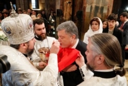 Ukrainian President Petro Poroshenko takes part in a religious ceremony after a service marking Orthodox Christmas and celebrating the independence of the Orthodox Church of Ukraine at St. Sophia's Cathedral in Kyiv on January 7, 2019.