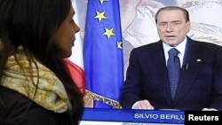 Женщина следит за телевыступлением экс-премьера Италии Сильвио Берлускони, 13 ноября 2011