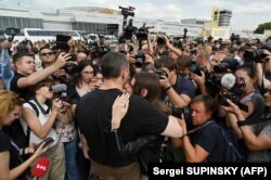 Reporters surround Ukrainian film director Oleh Sentsov (center) as he hugs his daughter, Alina.