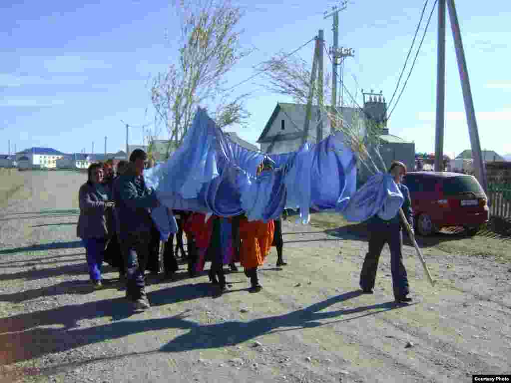 Members of the groom&#39;s family bring a wedding curtain, which will hang in the couple&#39;s bedroom, to the house where the bride is hiding.