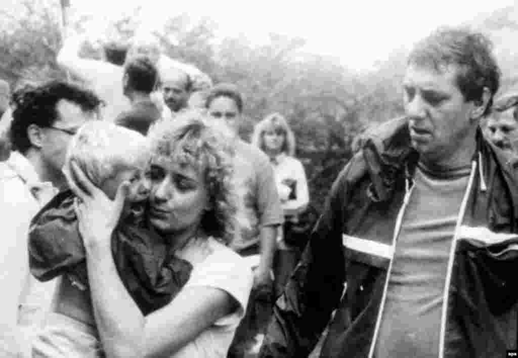 Жінка зі Східної Німеччини пригортає до себе заплакану дитину. З дитиною жінка змогла возз&rsquo;єднатися після розлуки, коли вони загубили одне одного під час перетину австрійсько-угорського кордону 19 серпня 1989 року