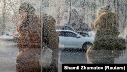 People wait at a bus stop on a cold day in Almaty.