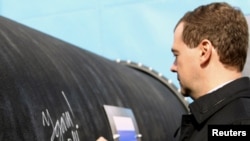 Russian President Dmitry Medvedev writes 'Good Luck!' on a section of the Nord Stream pipeline.