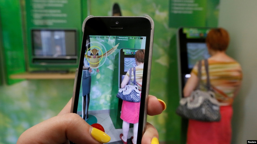A Russian woman plays Pokemon Go while someone uses an ATM in Krasnoyarsk, Russia.