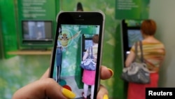 A Russian woman plays Pokemon Go while someone uses an ATM in Krasnoyarsk, Russia.