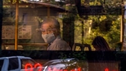 Мужчина в защитной маске смотрит в окно автобуса.