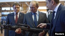 Президент России Владимир Путин держит в руках оружие во время посещения оружейного завода в Туле. 20 января 2014 года.