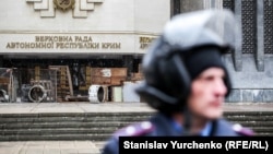 Сотрудник МВД стоит возле здания крымского парламента в Симферополе, который захватили российские военные 27 февраля 2014 года