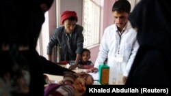 A man and his son look as another son is being treated at a malnutrition treatment center in Sanaa, November 4, 2017