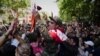 A soldier who has joined protests in Yerevan is carried above the crowd after being given a red rose.