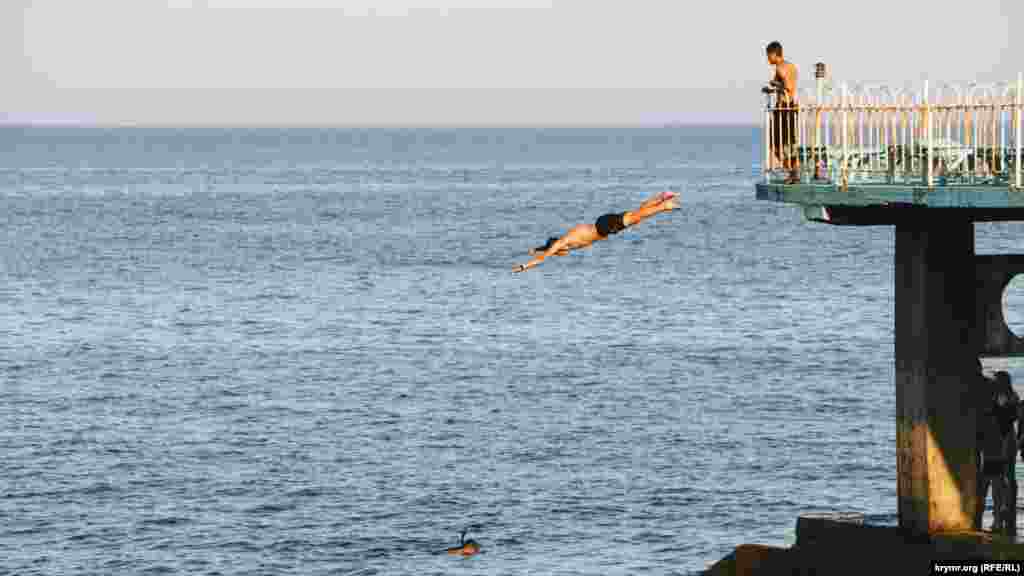 Бесстрашный молодой человек ныряет в море с высоты в несколько метров