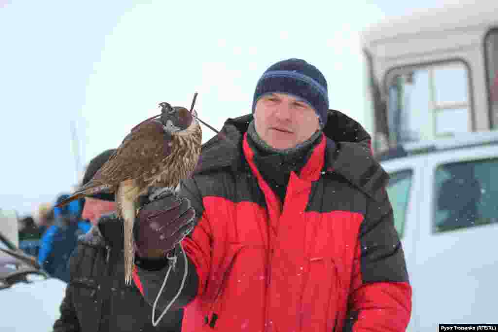 Some Russian falconers visited the tournament, but none was able to compete because of the difficulty involved in transporting birds of prey across borders. Here, a Russian falconer holds a bird belonging to one of the Kazakh competitors.&nbsp;