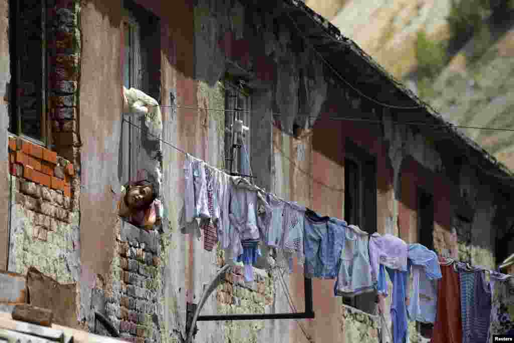 A girl looks out of the window of an old apartment built for mine workers.