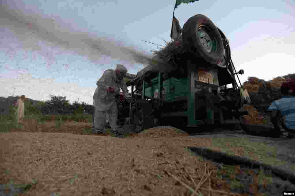 A man works on a wheat thresher in a field in the outskirts of Islamabad, Pakistan.