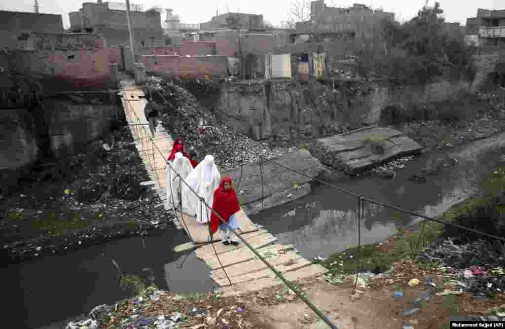 Villagers cross a makeshift bridge in a suburb of Peshawar, Pakistan. (AP/Mohammad Sajjad)