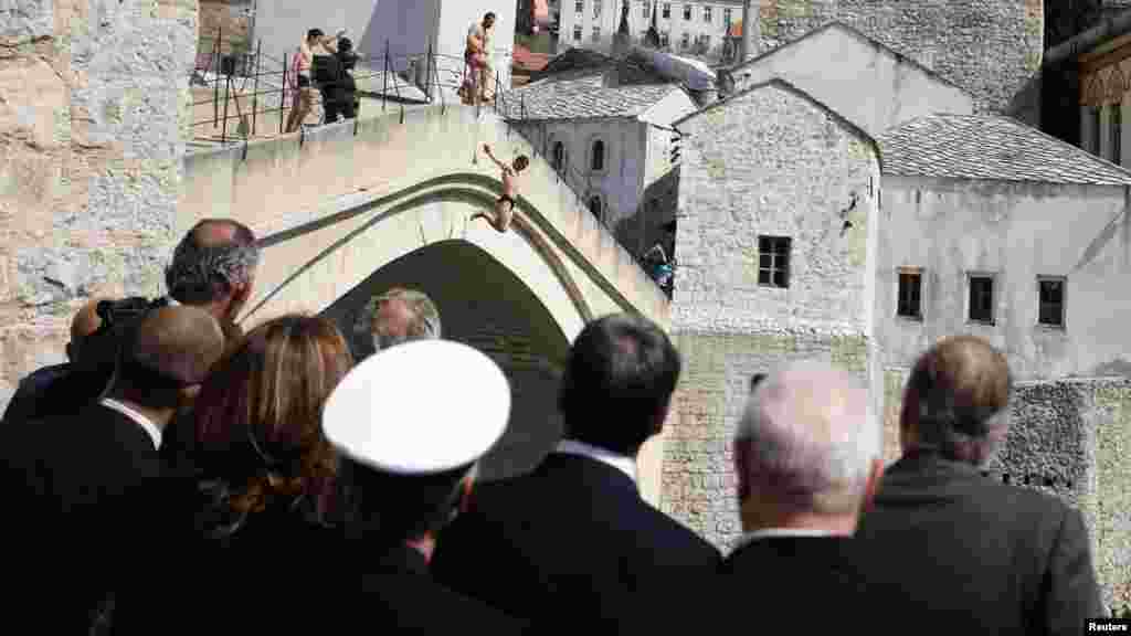 پادشاه اسپانیا خوان کارلوس، (سمت راست) با اعضای هیئت خود در حال نگاه به مردان که از پل قدیمی شهر تاریخی مُستار بوسنی در حال پرش به آب هستند. 
