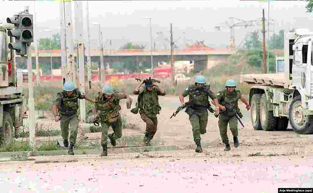 French and Ukrainian UN soldiers run for cover from sniper fire in downtown Sarajavo on July 21, 1994.