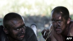 Rescuers smoke as they rest during a break in relief efforts following a blast at a coal mine in the Luhansk region on July 29, which killed dozens of miners. 