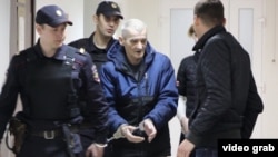 Юрий Дмитриев в окружении полицейских