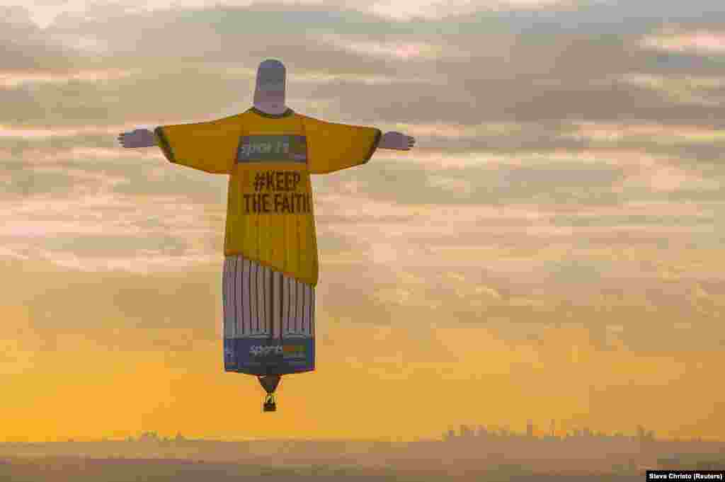 A balloon shaped like the famous Christ The Redeemer statue that overlooks the Brazilian city of Rio de Janeiro floats at sunrise above Sydney, Australia as part of an advertisement campaign for an online betting company. (Reuters/Steve Christo)