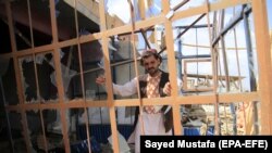 FILE: An Afghan man surveys the damaged caused by the a suicide bomb attack in Ghazni in May.