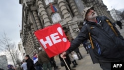 Un protestatar în fața sediului guvernului la Belgrad