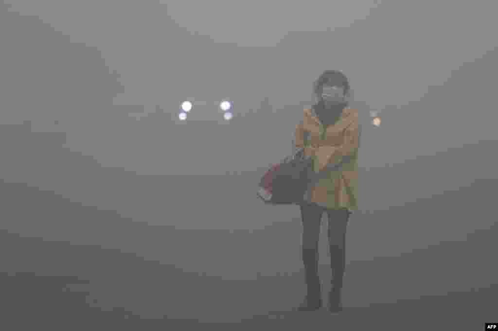 Китай – жінка в масці для захисту від смогу на вулиці Харбіна (північний схід Китаю). Через смог видимість у місті впала до 10 метрів. Фото 21 жовтня 2013 року