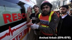 A rescue worker assists an injured student from the shooting in Peshawar, Pakistan, on December 1.