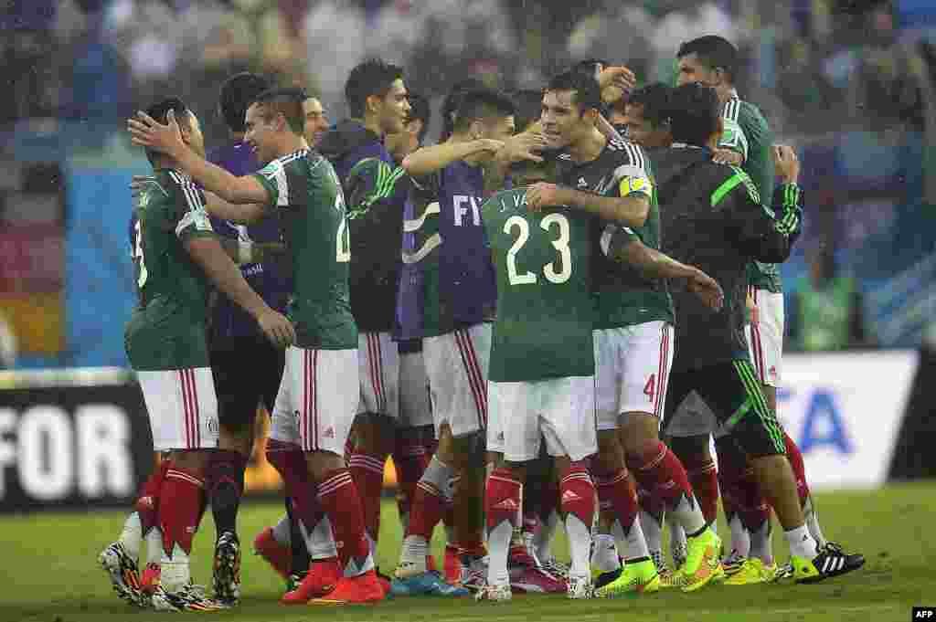 Mexican players celebrate after winning 1-0 the Group A football match between Mexico and Cameroon at the Dunas Arena in Natal during the 2014 FIFA World Cup on June 13, 2014. AFP PHOTO / PIERRE-PHILIPPE MARCOU