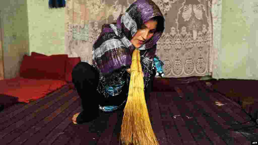 Pari, 33, sweeps her house in the Afghan city of Herat. She lost her hands when she was 7 when her village was bombed during the Soviet invasion. She sells handicrafts to feed her three children and her elderly husband. (AFP/Aref Karimi)