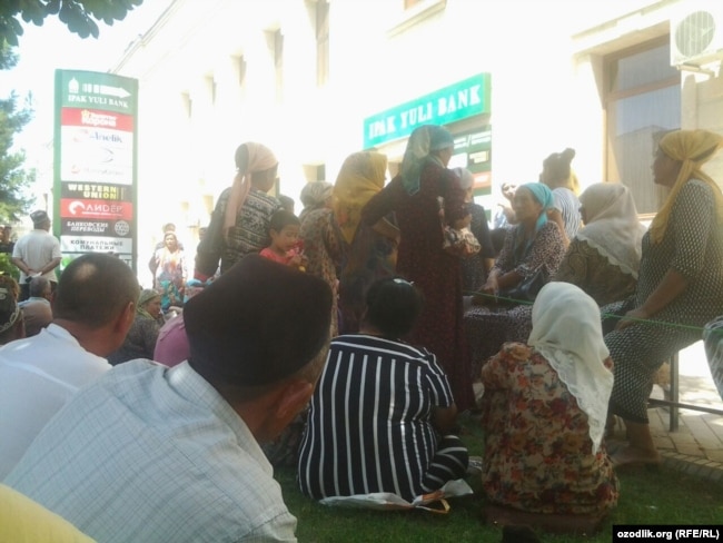 Люди стоят в очереди перед зданием филиала банка Ипак йули в городе Андижане, чтобы получить денежный перевод.