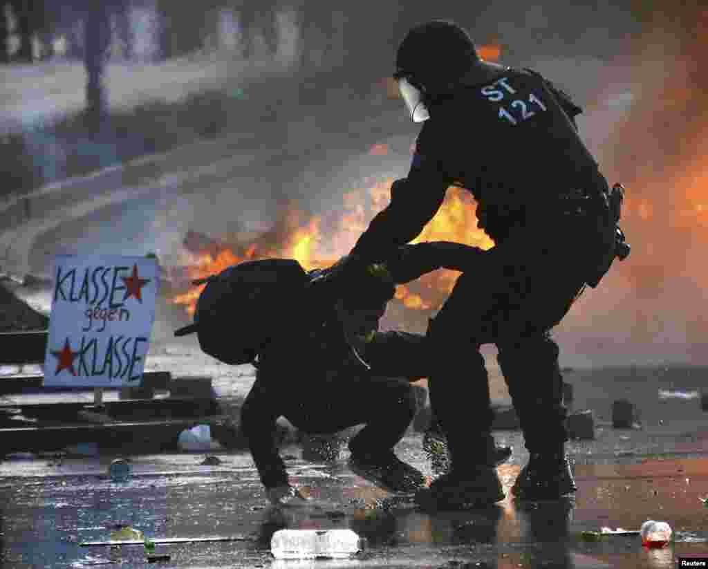 Polisiýa Ýewropanyň Merkezi bankynyň binasynyň golaýynda, Frankfurtda onuň täze ofisleriniň resmi açylyşynyň öň ýanynda antikapitalist protestçini tutýar, 18-nji mart. (Roýters/​Kai Pfaffenbach)