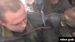 Givi uses a knife to cut the chevrons from the jackets of the prisoners, before stuffing them into their mouths.