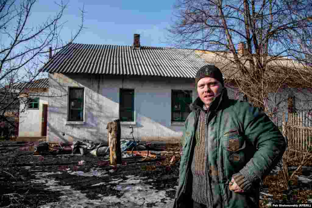 Ivan stands in front of his family's house in the Petrovskiy district of Donetsk. He is unemployed, and the only family income comes from welfare payments for his three children.