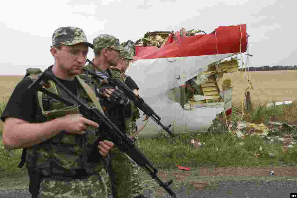 Armed pro-Russian militants walk past a large piece of wreckage in a field near Donetsk.