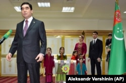 Turkmen President Gurbanguly Berdymukhamedov, speaks to journalists after casting his ballot as his son Serdar (second right) stands with other family members at a polling station in Ashgabat in February 2017.