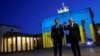 Kancelari gjerman, Olaf Scholz, dhe presidenti francez, Emmanuel Macron, pranë Portës së Brandenburgut, e ndriçuar me ngjyrat e flamurit ukrainas. Berlin, 9 maj 2022.