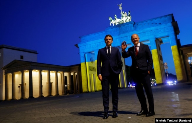 Il presidente francese Emmanuel Macron (a sinistra) e il cancelliere tedesco Olaf Scholz visitano la Porta di Brandeburgo mentre è illuminata con i colori della bandiera ucraina, a Berlino il 9 maggio 2022.