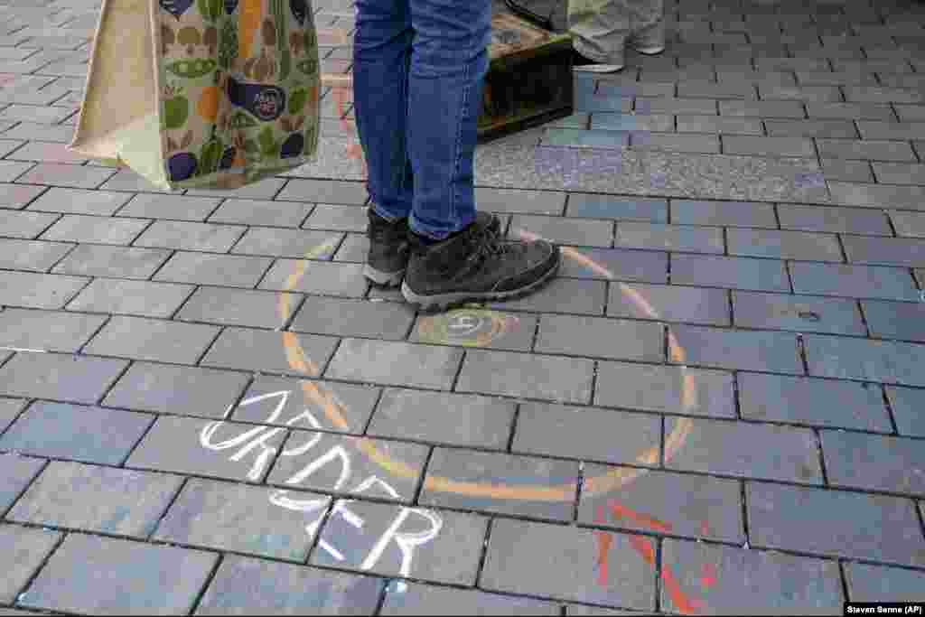 A shopper stands in a designated safe spot outside Safe Supply: Outdoor Grocery Store in Somerville, Massachusetts. The store takes reservations, requires customers to wash their hands, and offers them the opportunity to shop without touching items.