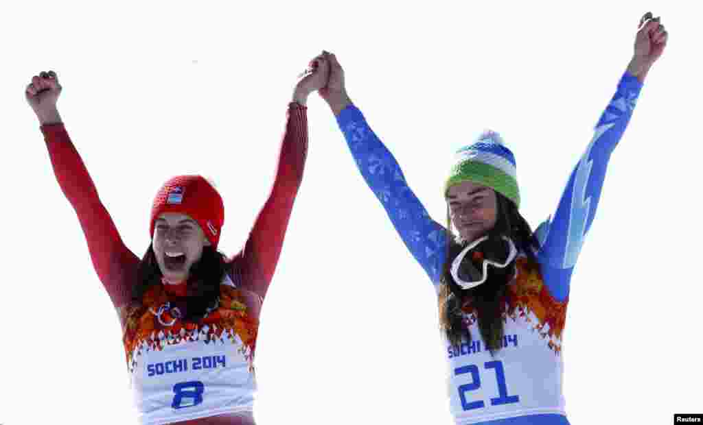 Joint winners Dominique Gisin of Switzerland (left) and Tina Maze of Slovenia celebrate on the podium after the women&#39;s alpine-skiing downhill event during the flower ceremony.