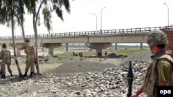 Pakistani soldiers inspect a bridge over the Kurram River. Can development go forward when military operations are driving people from their homes?