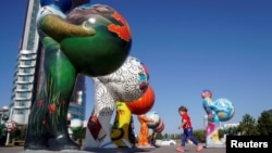Астанадағы EXPO-2017 көрмесіне қатысушы елдерді бейнелейтін мүсіндердің қасынан өтіп бара жатқан бала. 29 қыркүйек 2016 жыл.