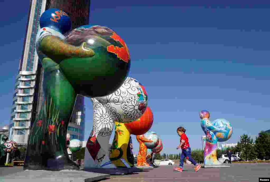 Kazakhstan -- A boy runs past figures symbolizing participant countries in the Expo 2017 in central Astana, the host city of next year&#39;s exhibition. (Reuters/Shamil Zhumatov)