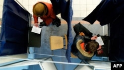 Voters prepare to cast their ballots at a polling station as Latvia holds a controversial referendum on whether to make Russian its second official language on February 18.