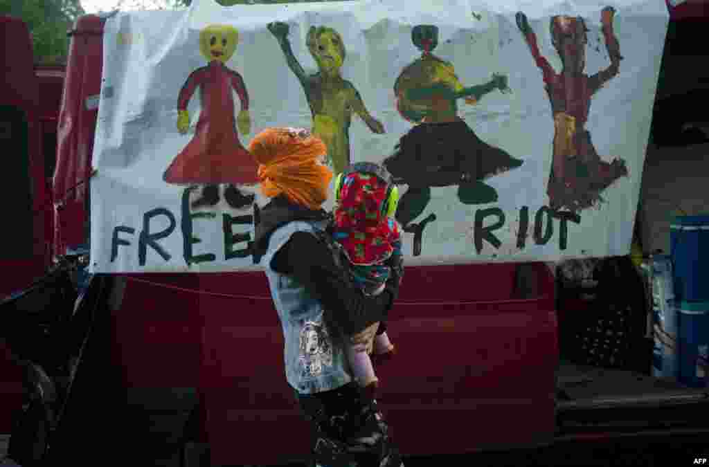 A mother holding her baby walks past a car with a banner reading "Free Pussy Riot" during a demonstration supporting the Russian performance artists Pussy Riot in Prague. (AFP/Michal Cizek)