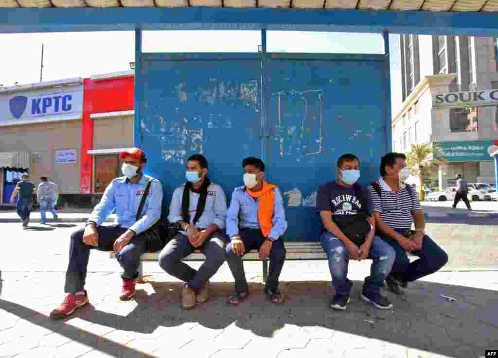 Люди в защитных масках в городе Кувейт&nbsp;ждут&nbsp;автобус. 2 марта 2020 года. 
