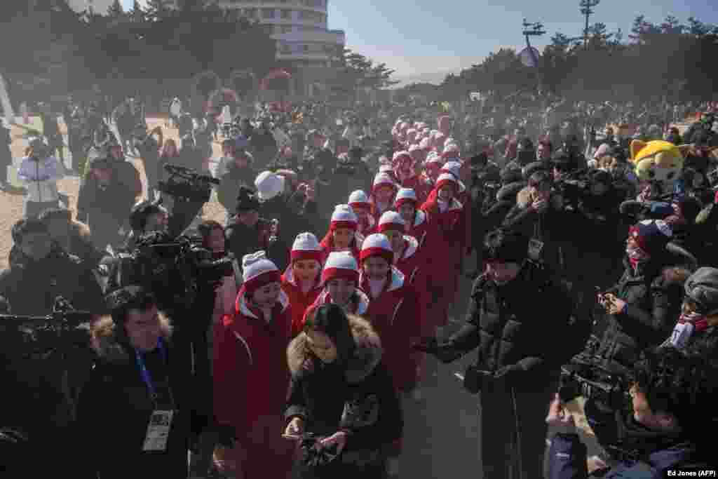 North Korean cheerleaders are surrounded by media as they attempt to walk on Gyeongpo Beach in Gangneung, South Korea. The North's 229-strong cheering squad, dubbed the "Army of Beauties," have drawn a lot of attention since arriving for the Pyeongchang Winter Olympics last week. (AFP/Ed Jones)
