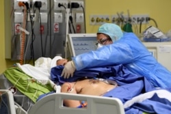 Медик оказывает помощь больному COVID-19 в одной из больниц Милана