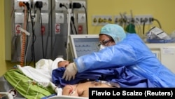 Un cadru medical îngrijind un pacient bolnav de COVID-19 la secția de terapie intensivă a unui spital din Milano, Italia