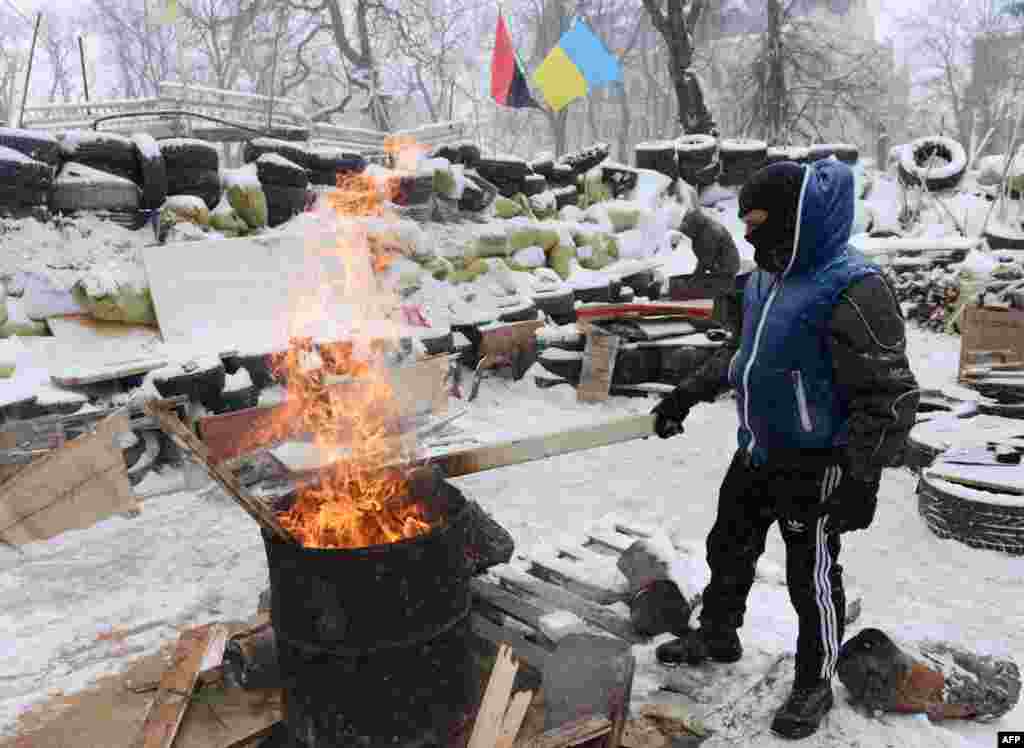 Украинаның көнбатышындагы Львов шәһәрендә демонстрацияче хакимият бинасы янындагы баррикадада ут яндырып җылына.